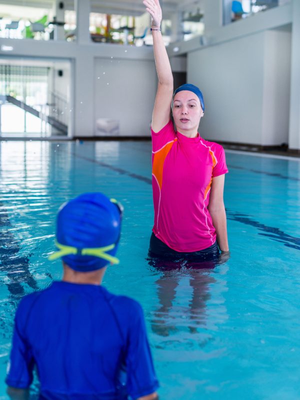 Swimming lesson. Cute little boy learning to swim with swimming instructor
